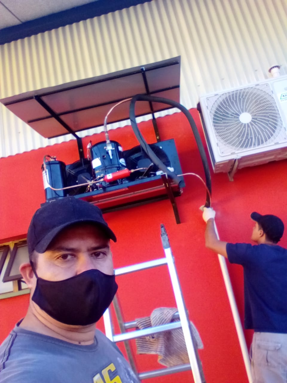 Dos tecnicos reparando un aire acondicionado
